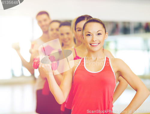 Image of group of smiling people with dumbbells in the gym