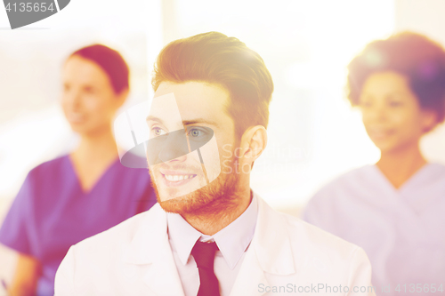 Image of happy doctor over group of medics at hospital