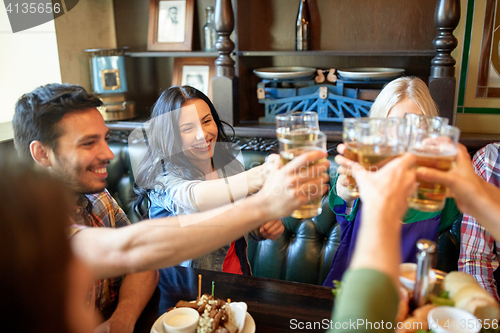 Image of happy friends drinking beer at bar or pub