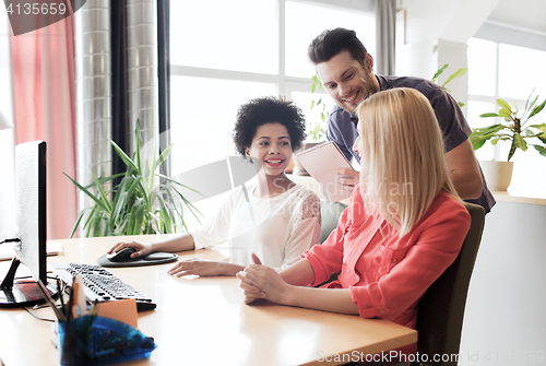 Image of happy creative team with computer in office