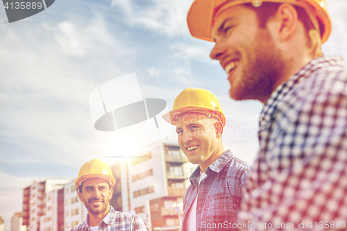 Image of group of smiling builders in hardhats outdoors