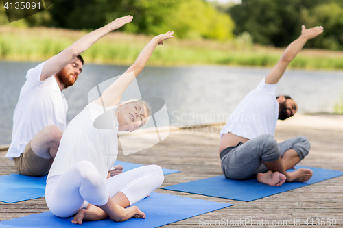 Image of group of people making yoga exercises outdoors