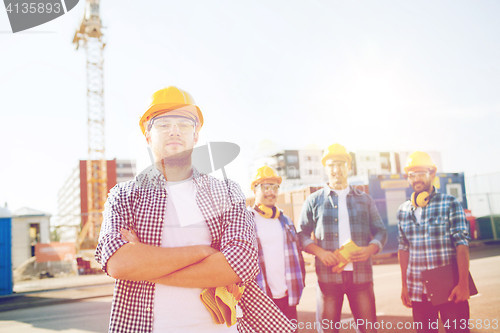 Image of group of smiling builders in hardhats outdoors