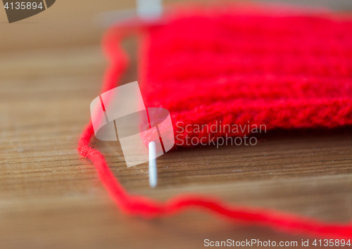 Image of hand-knitted item with knitting needles on wood