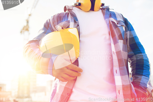 Image of close up of builder holding hardhat on building