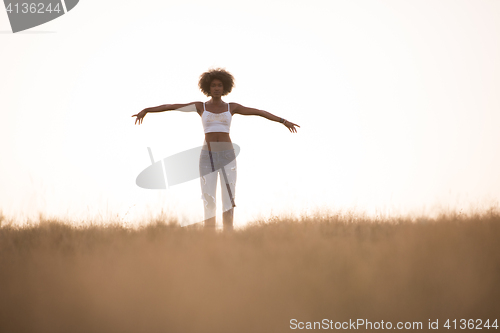 Image of young black girl dances outdoors in a meadow
