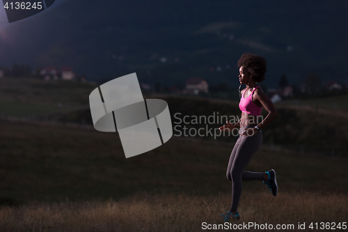 Image of Young African american woman jogging in nature