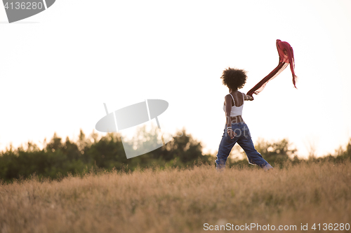 Image of black girl dances outdoors in a meadow