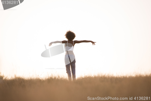 Image of young black girl dances outdoors in a meadow