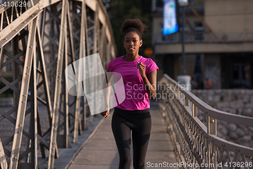 Image of african american woman running across the bridge