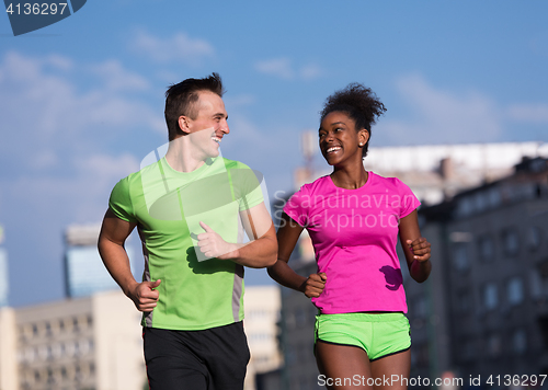 Image of young smiling multiethnic couple jogging in the city