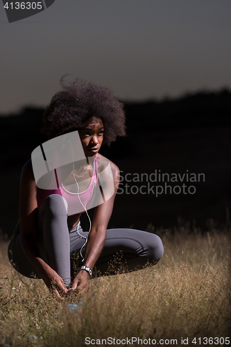 Image of black woman runner tightening shoe lace