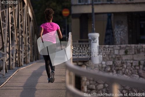 Image of african american woman running across the bridge