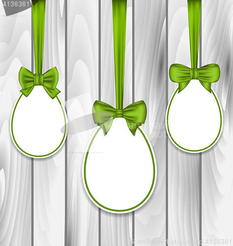 Image of Easter three papers eggs wrapping green bows on grey wooden back