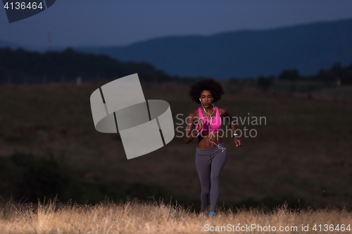 Image of Young African american woman jogging in nature