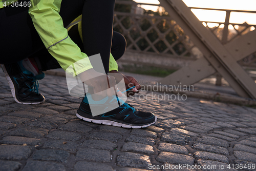 Image of African american woman runner tightening shoe lace