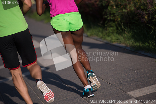 Image of young smiling multiethnic couple jogging in the city