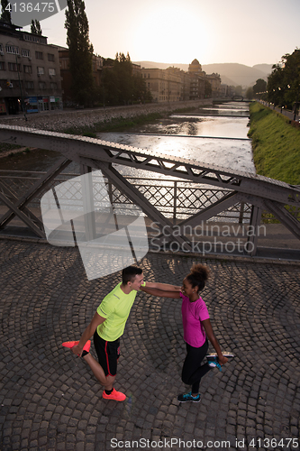 Image of jogging couple warming up and stretching in the city