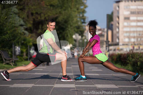 Image of jogging couple warming up and stretching in the city