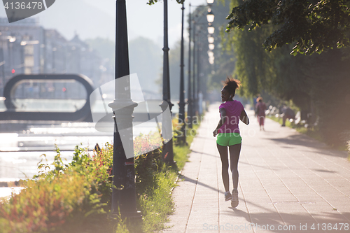 Image of african american woman jogging in the city