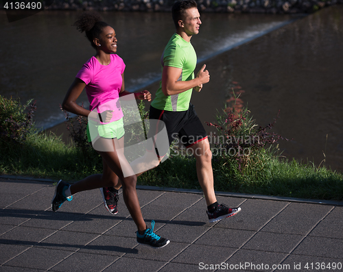 Image of young smiling multiethnic couple jogging in the city