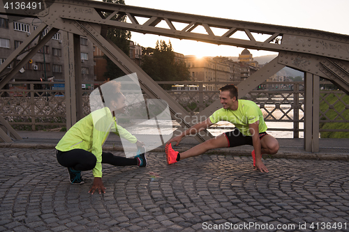 Image of jogging couple warming up and stretching in the city