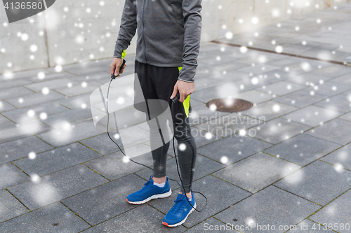 Image of close up of man exercising with jump-rope outdoors