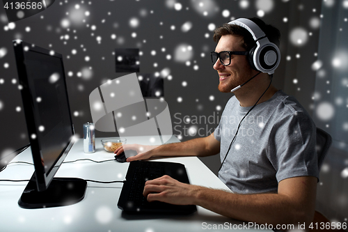 Image of man in headset playing computer video game at home