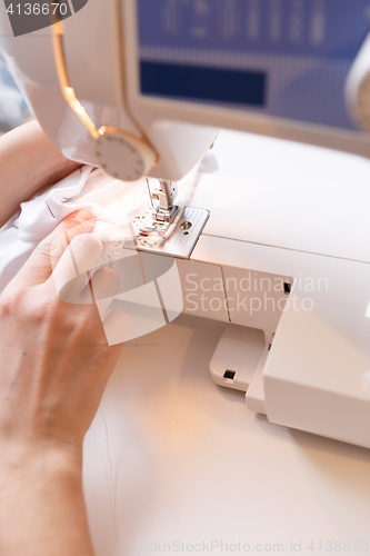 Image of Seamstress sewing white cloth close-up