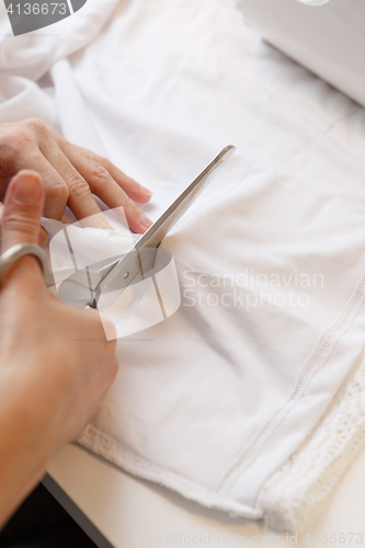 Image of Woman cuts cloth with scissors