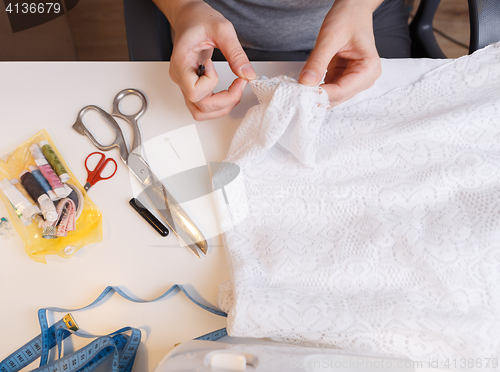 Image of Seamstress unrips fabric near sewing-machine