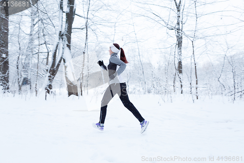 Image of Woman running in winter woods