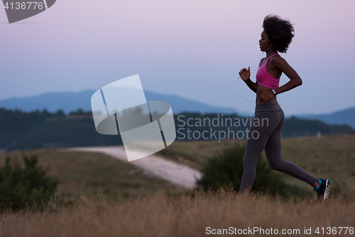 Image of Young African american woman jogging in nature