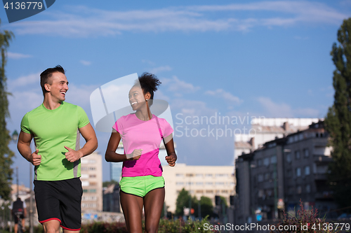 Image of young smiling multiethnic couple jogging in the city