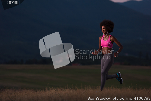 Image of Young African american woman jogging in nature