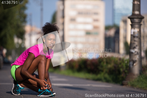 Image of African american woman runner tightening shoe lace