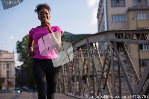 Image of african american woman running across the bridge