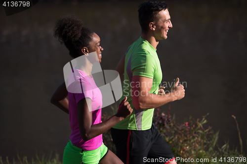 Image of young smiling multiethnic couple jogging in the city