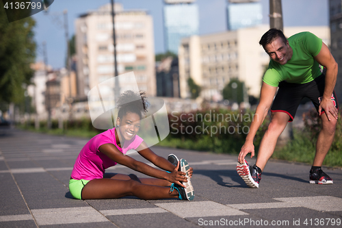 Image of jogging couple warming up and stretching in the city