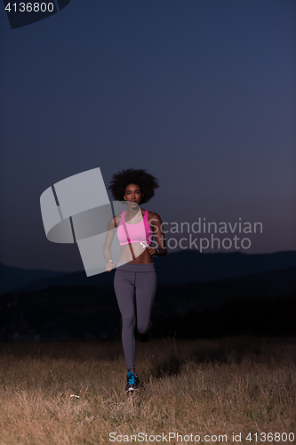 Image of Young African american woman jogging in nature