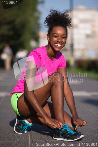 Image of African american woman runner tightening shoe lace