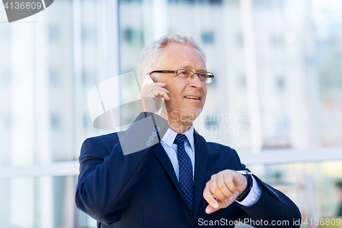 Image of senior businessman calling on smartphone in city