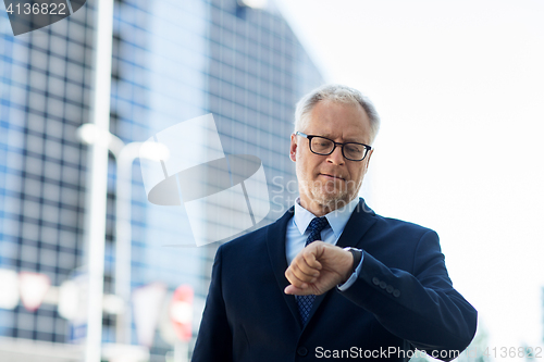 Image of senior businessman checking time on his wristwatch