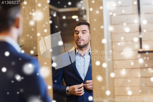 Image of man trying jacket on at mirror in clothing store