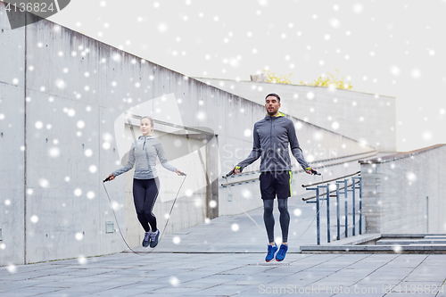 Image of man and woman exercising with jump-rope outdoors