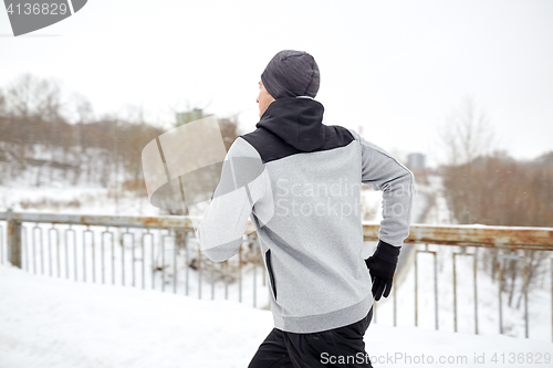 Image of man running along snow covered winter bridge road