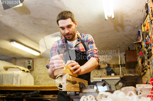 Image of carpenter working with plane and wood at workshop