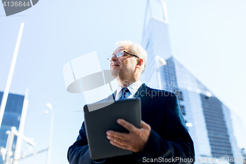 Image of senior businessman with tablet pc on city street