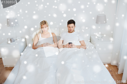 Image of couple with smartphones in bed