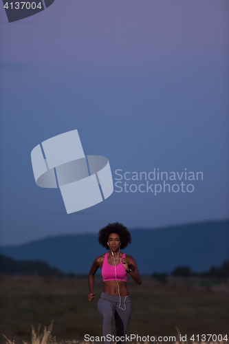 Image of Young African american woman jogging in nature